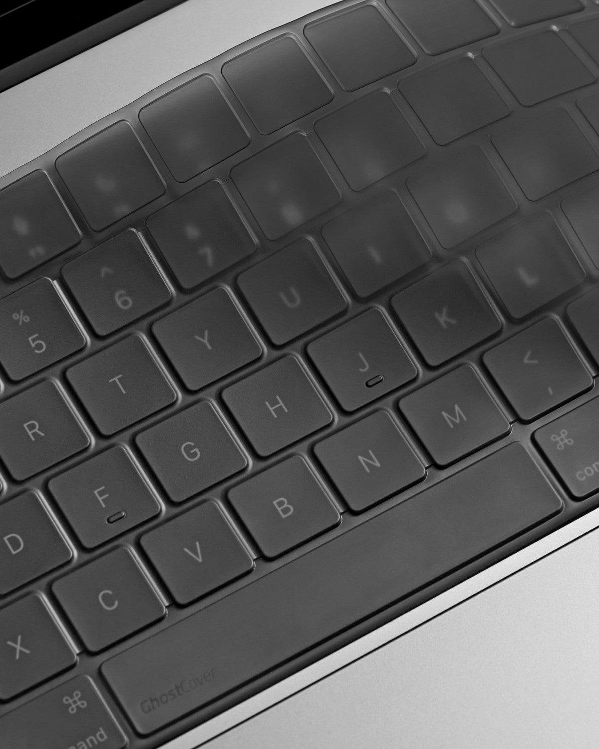 Low-angle close-up of tinted GhostCover FlexType on MacBook keys, showing its thin profile