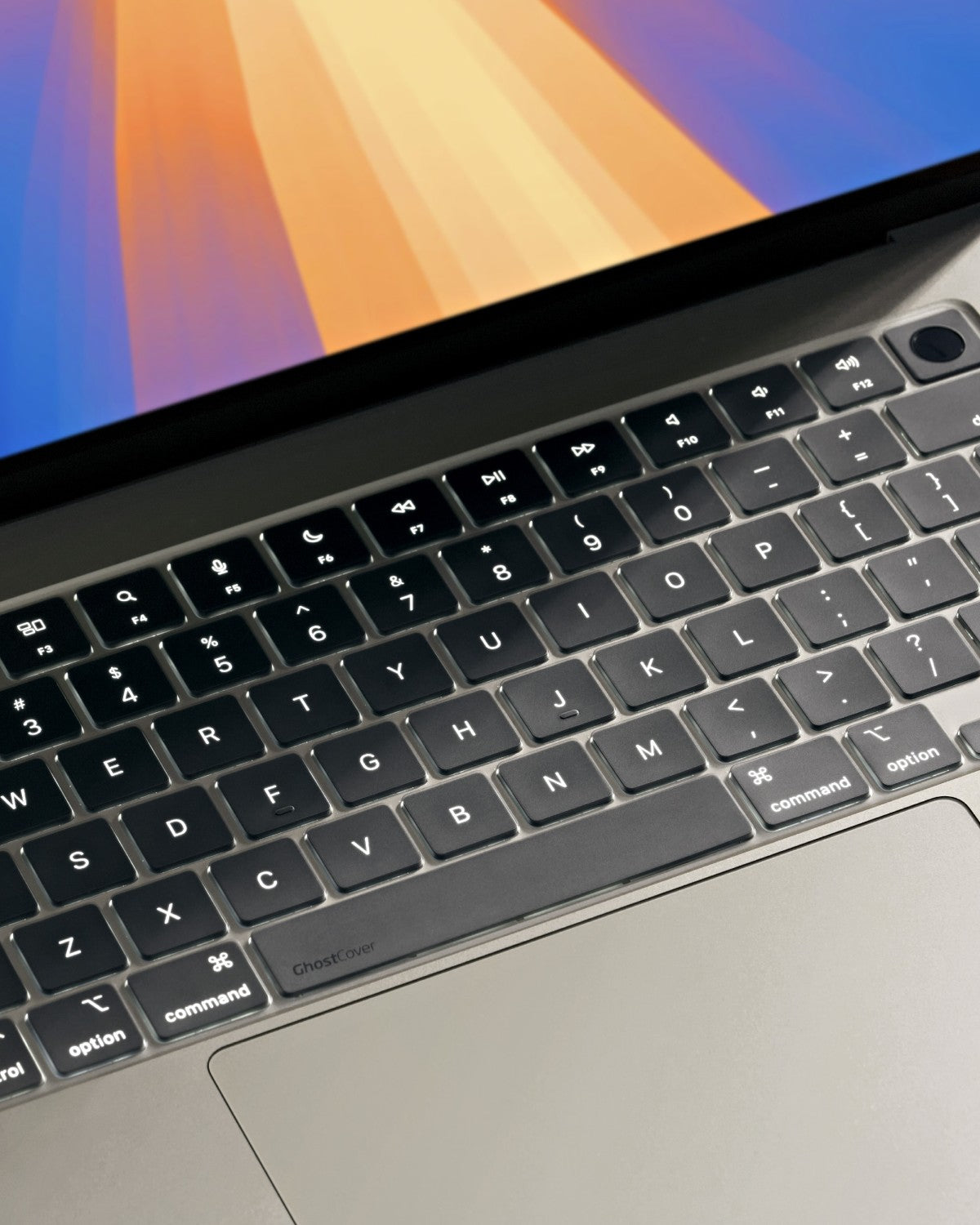 Close-up of a MacBook keyboard with GhostCover showing backlit keys shine through