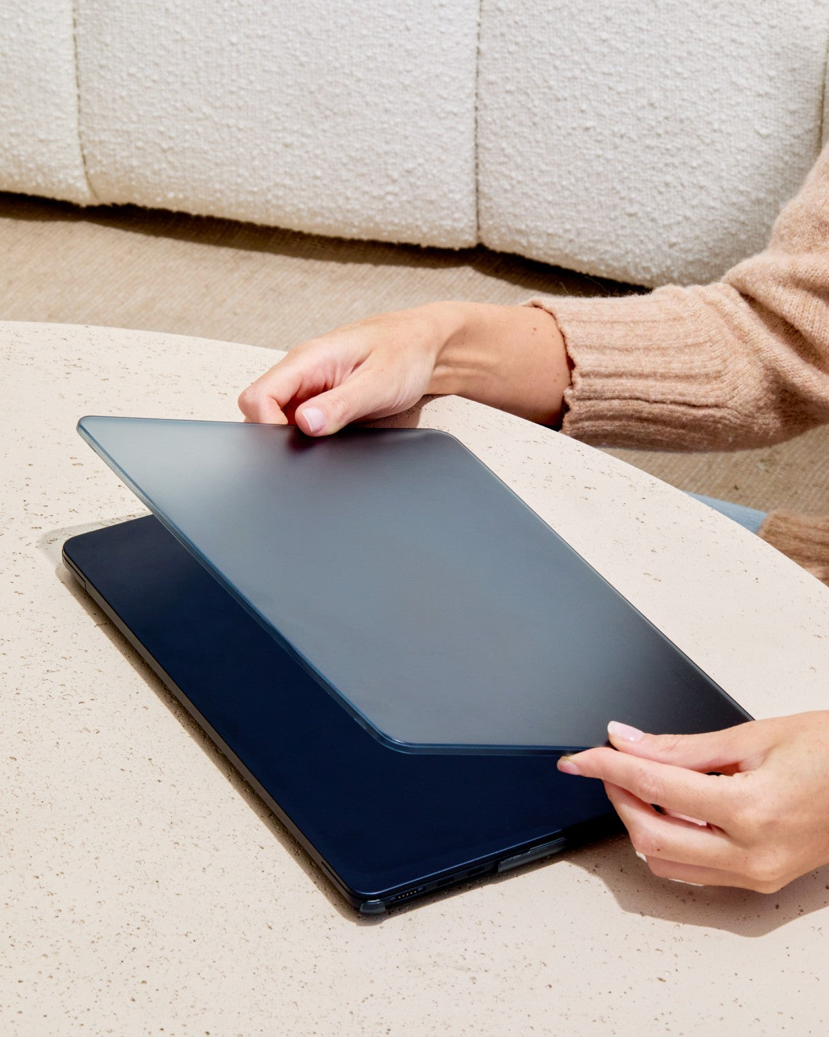 Hands installing the Midnight GhostShell Frost case top shell on a MacBook on a table