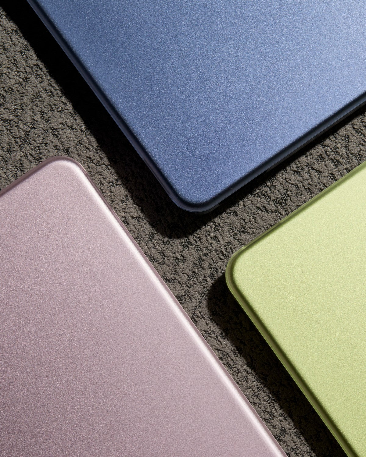 Indigo, Citrus, and Blush MacBook Neo laptops with matching-color GhostShell Frost protective hardshell cases.