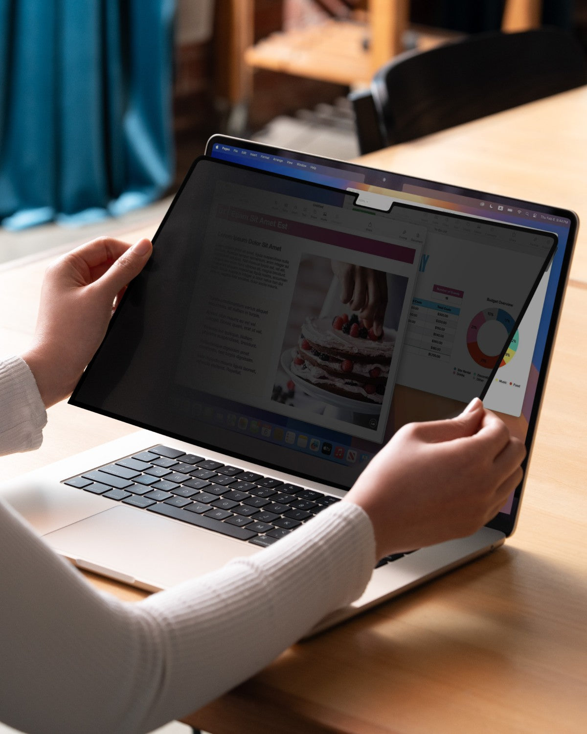 Person using a MacBook with GhostView privacy filter at a desk, screen readable straight on