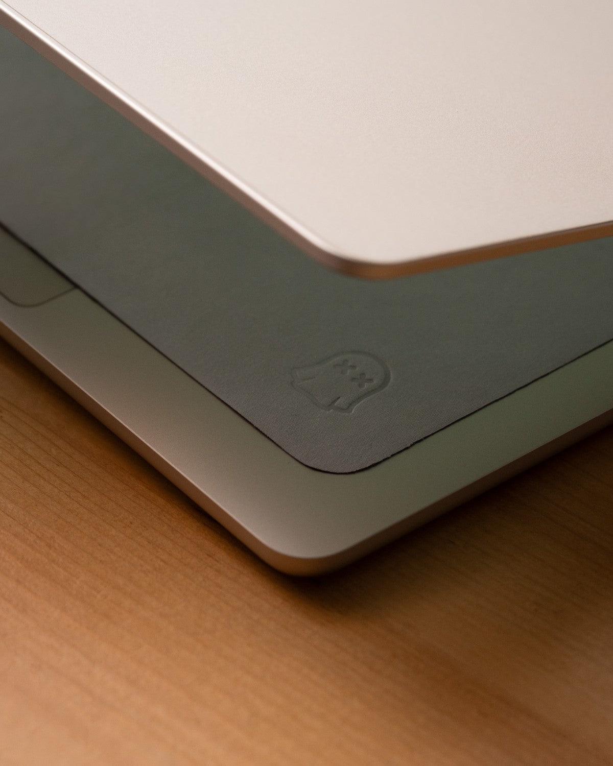 Close-up of a half open MacBook with the thin edge of the GhostBlanket liner, zoomed on the ghost logo