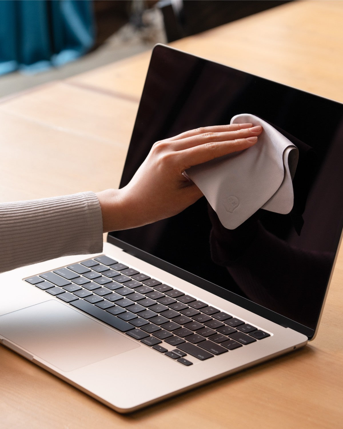 Hand cleaning a MacBook screen with the GhostBlanket microfiber cloth