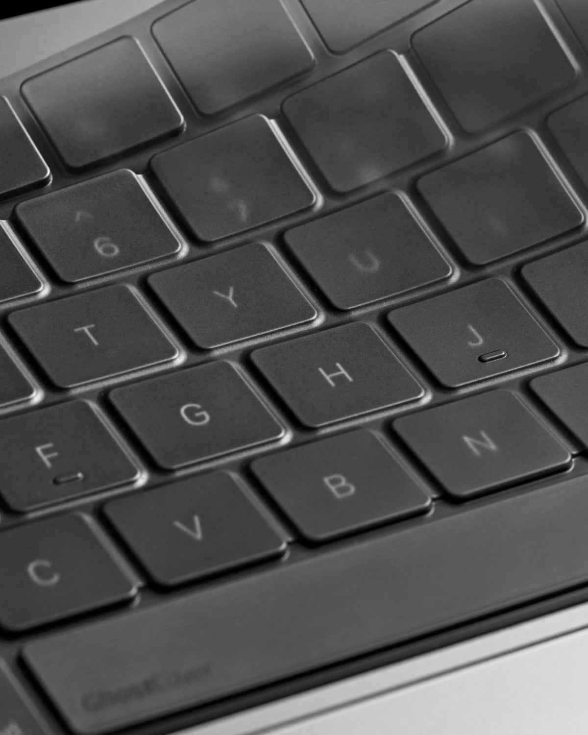 Close-up of tinted gray GhostCover FlexType keyboard protector half lifted showing its transparancy