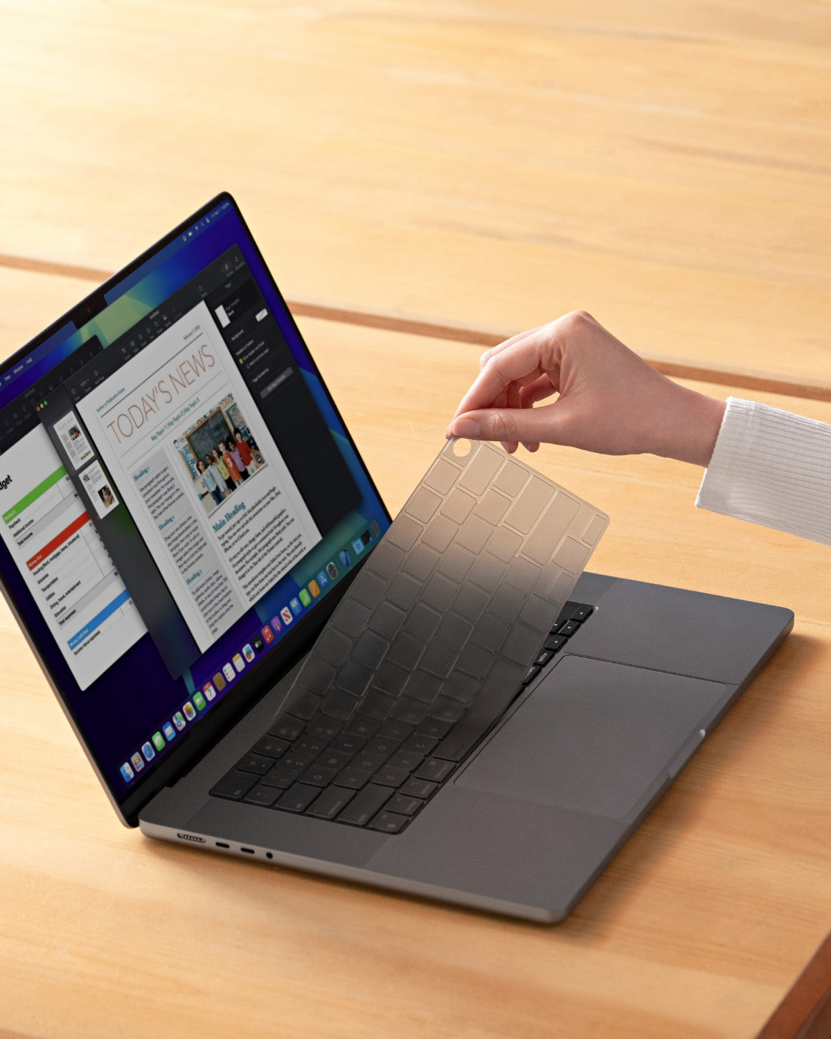 Hand lifting a GhostCover FlexType keyboard protector in tinted color off a MacBook Pro in space black