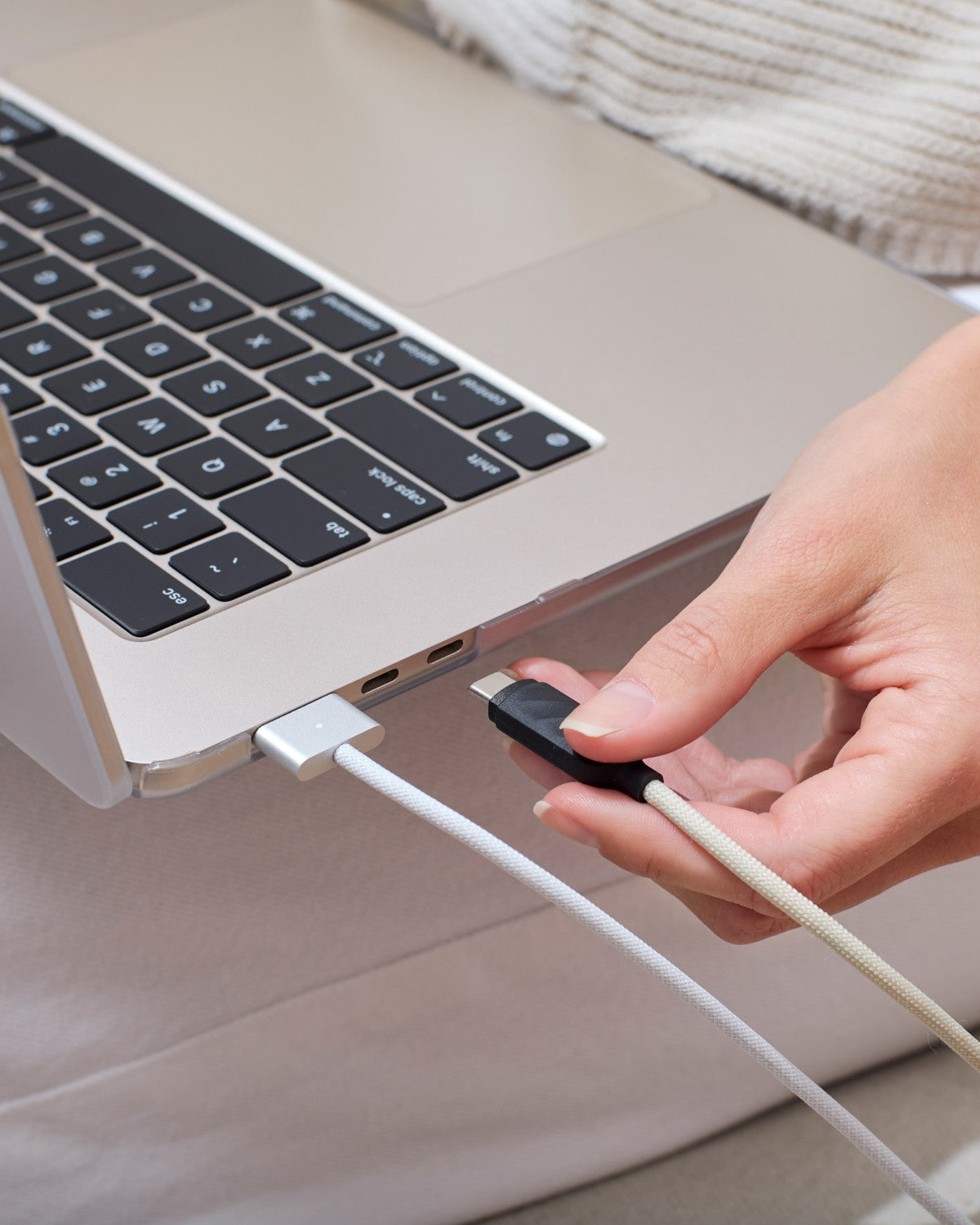 Hand plugging a USB-C cable into a MacBook wearing a GhostShell Frost case