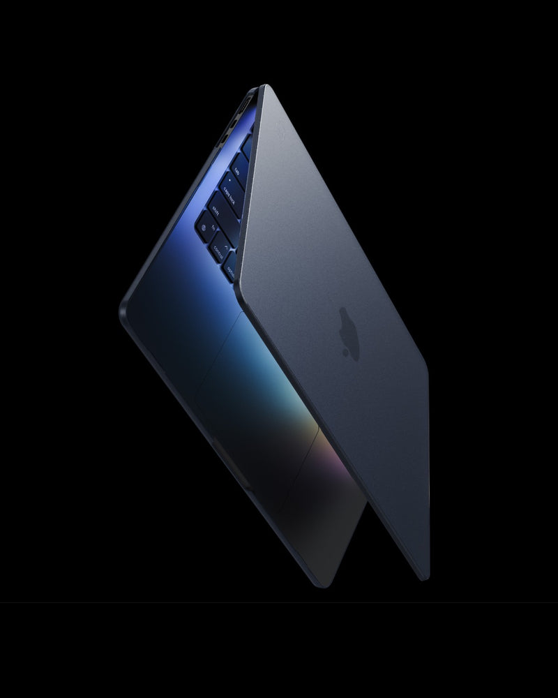 MacBook in a translucent Midnight GhostShell Frost case, lid open, on a dark background
