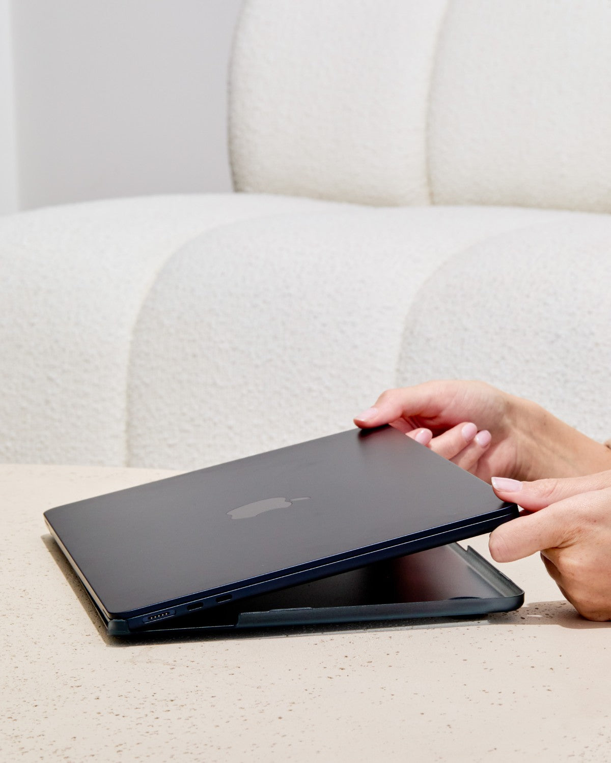 Hands snapping a translucent black GhostShell Frost case onto a MacBook Pro