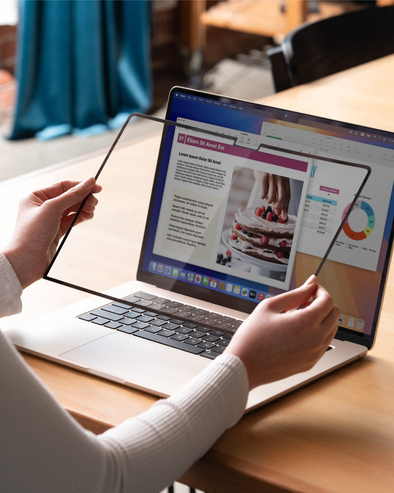 Hands attaching a GhostView detachable screen protector to a MacBook display