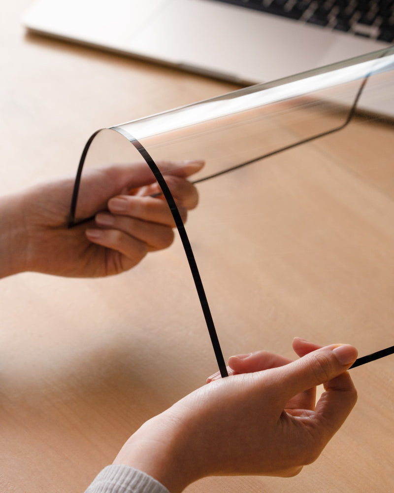 Hands flexing a GhostView screen protector to show how thin and flexible it is
