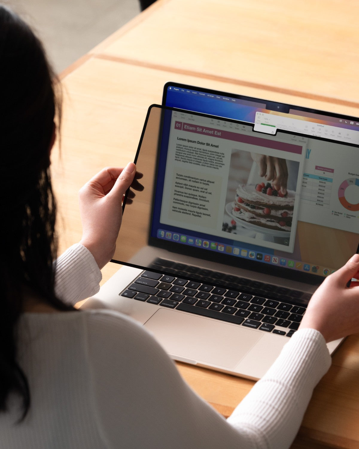 Woman putting on a GhostView privacy filter to a MacBook, screen clear when viewed straight on