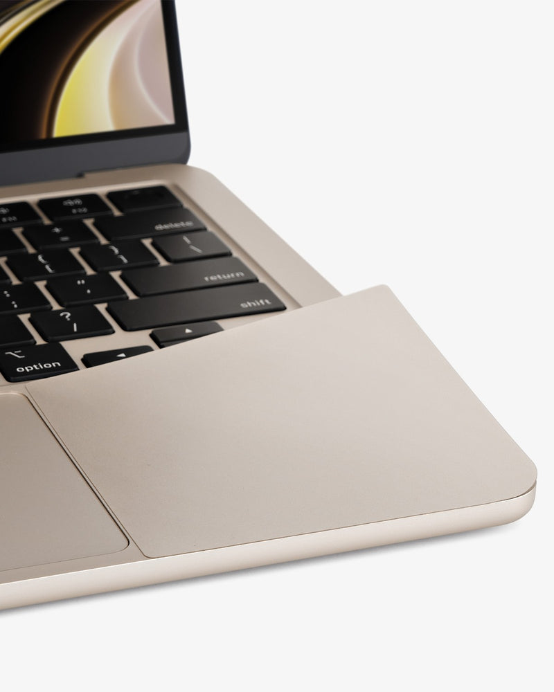 Close-up of a color-matched GhostShield palm rest protector blend into a Starlight MacBook Air.