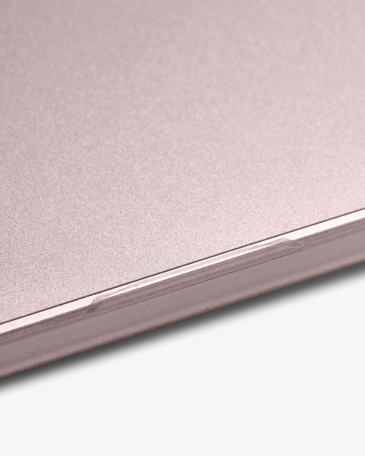 Edge of a Blush MacBook Neo where the GhostShield palm rest protector meets a GhostShell case