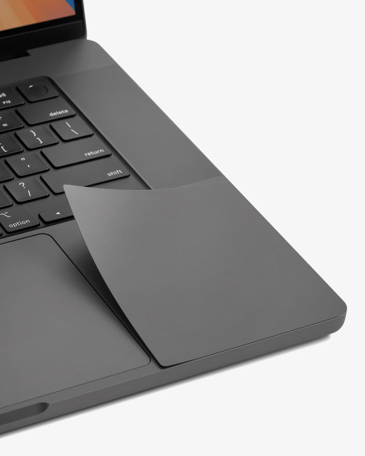 Close-up of a color-matched GhostShield palm rest protector on a Space Black MacBook Pro.